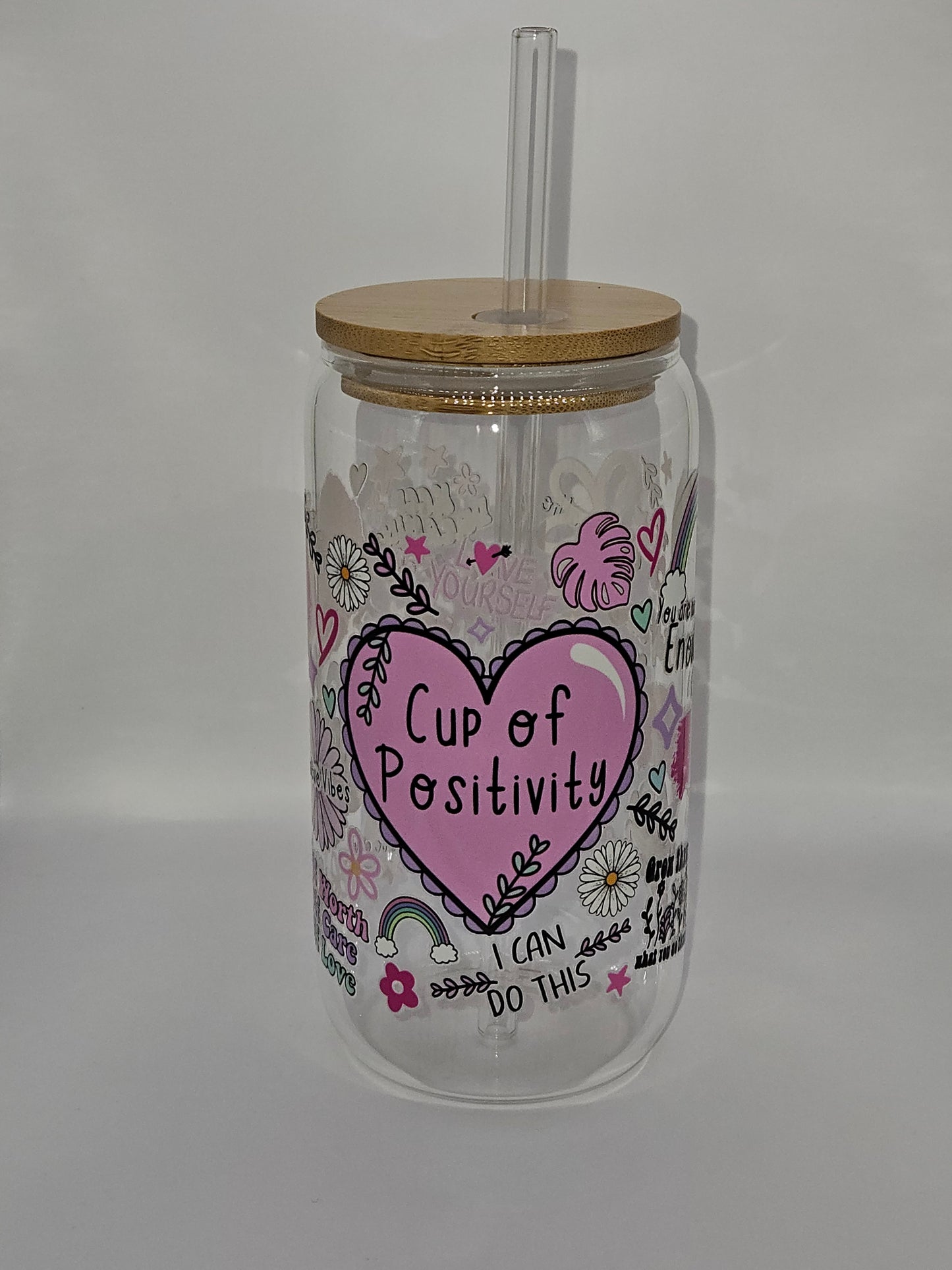 A 16oz heat-resistant glass cup with a floral design and the phrase 'Cup of Positivity' on the side, accompanied by a bamboo lid and a clear straw.